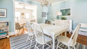 A dining area with a white table and chairs, a chandelier, and a mirror above the table.