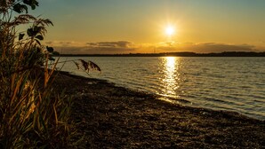 Ein Sonnenuntergang über ruhigem Wasser mit einer Küstenlinie.