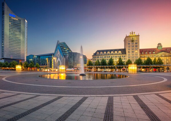 A city square with a modern building, a fountain, and historic architecture.