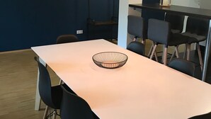 Ein Essbereich mit einem langen Tisch, schwarzen Stühlen und einer hängenden Leuchte.