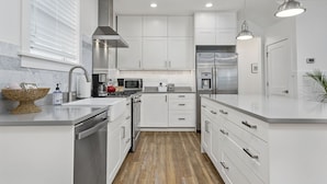 Una cocina moderna con armarios blancos, electrodomésticos de acero inoxidable y piso de madera.