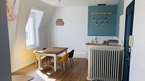 Une cuisine moderne avec une table et des chaises en bois, un mur d’accent bleu et un radiateur.