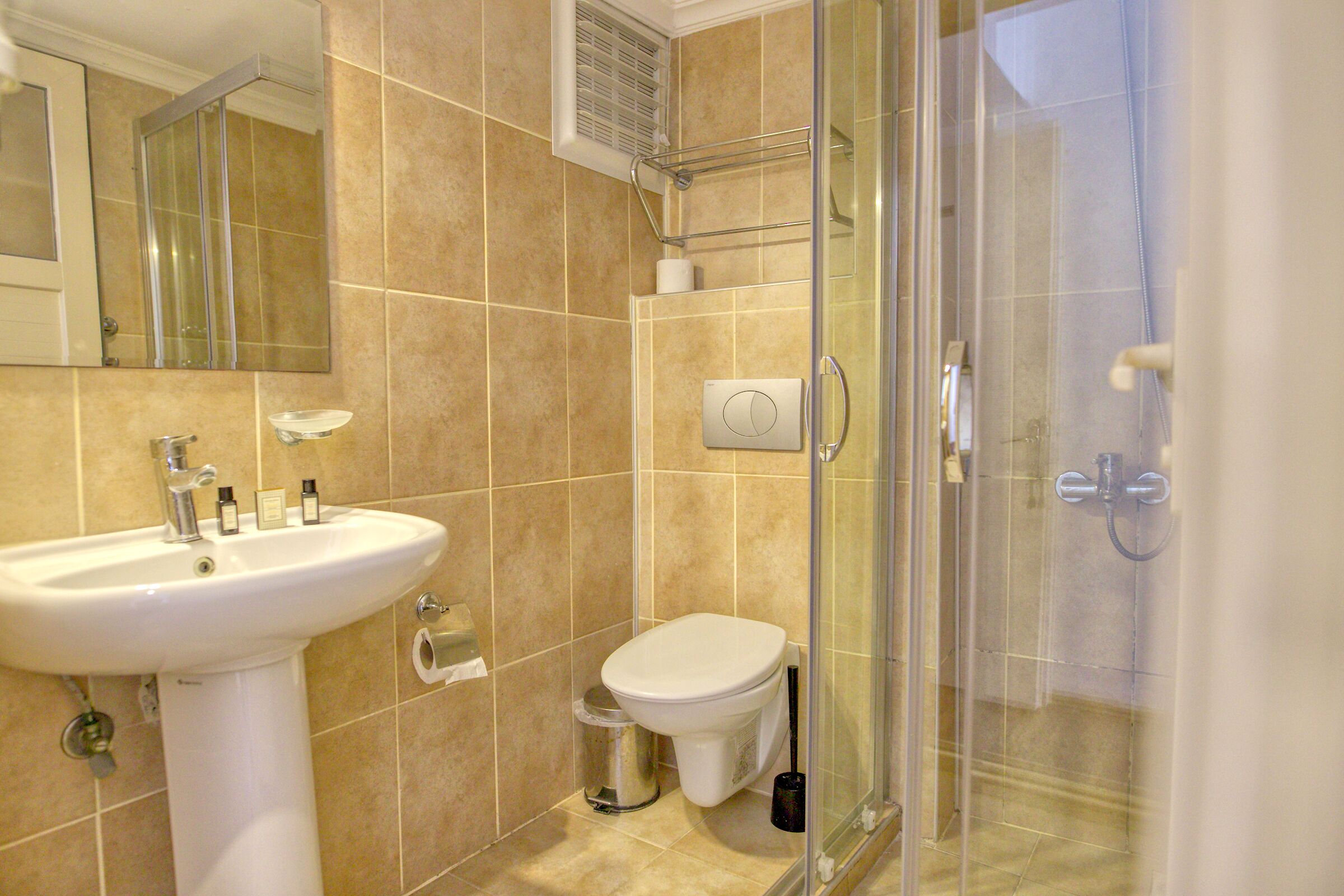 A bathroom with a sink, toilet, and glass shower enclosure.