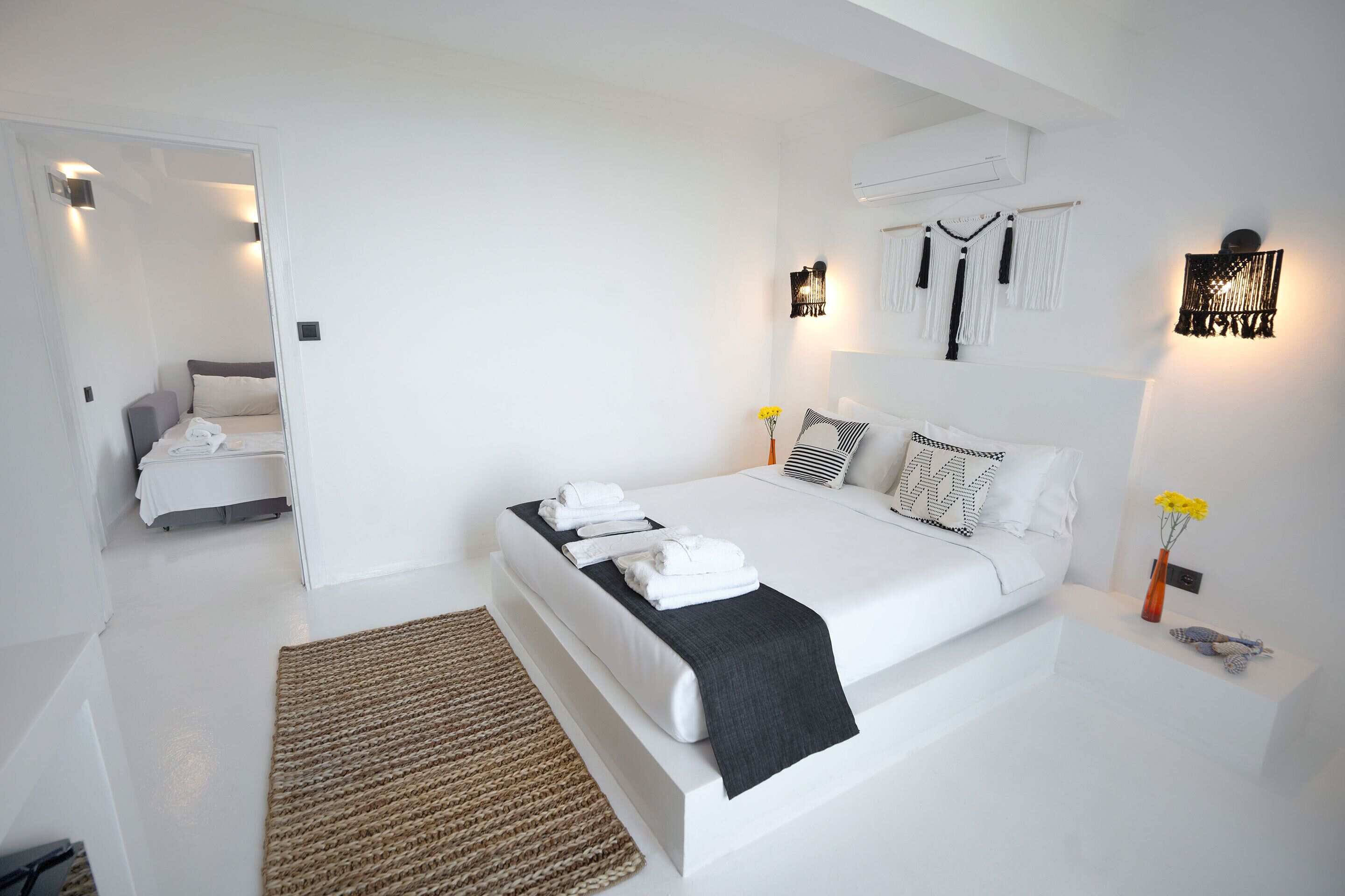 Un dormitorio moderno con una cama grande, mesitas de noche, una lámpara de noche y un aire acondicionado instalado en la pared.