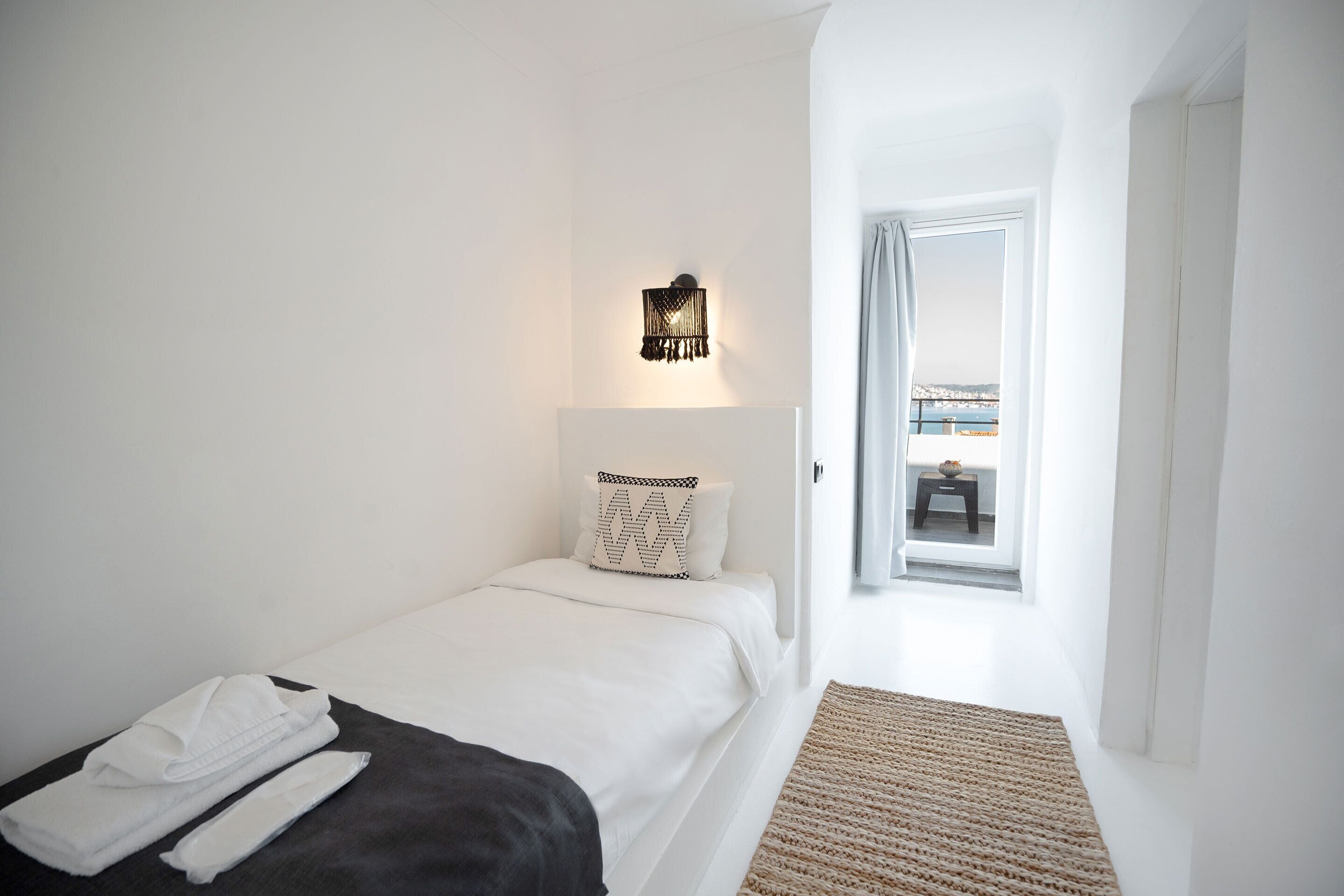 Une chambre d’hôtel avec un lit, une table de chevet, une lampe et une vue sur l’extérieur.