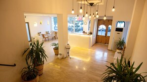 Un vestíbulo amplio con suelo de madera, una recepción y varias plantas en macetas.