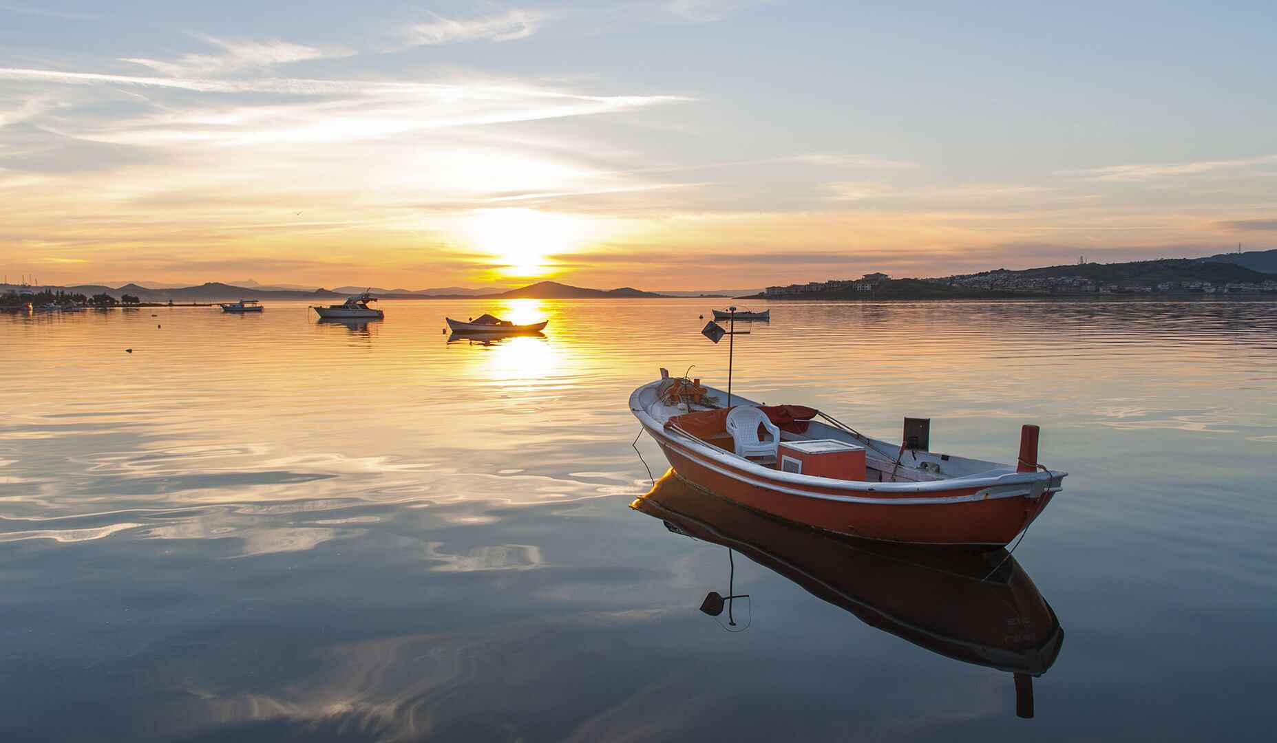 A calm lake with boats at sunset.