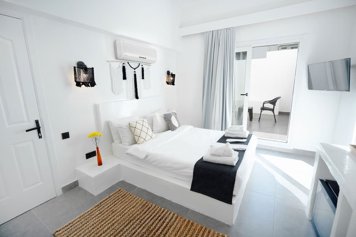 Une chambre à coucher moderne, équipée d’un lit, de tables de chevet, d’un téléviseur et d’une fenêtre avec des rideaux.