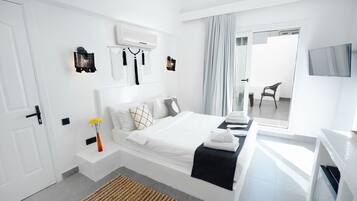 Un dormitorio moderno con cama, mesitas de noche, televisor y ventana con cortinas.
