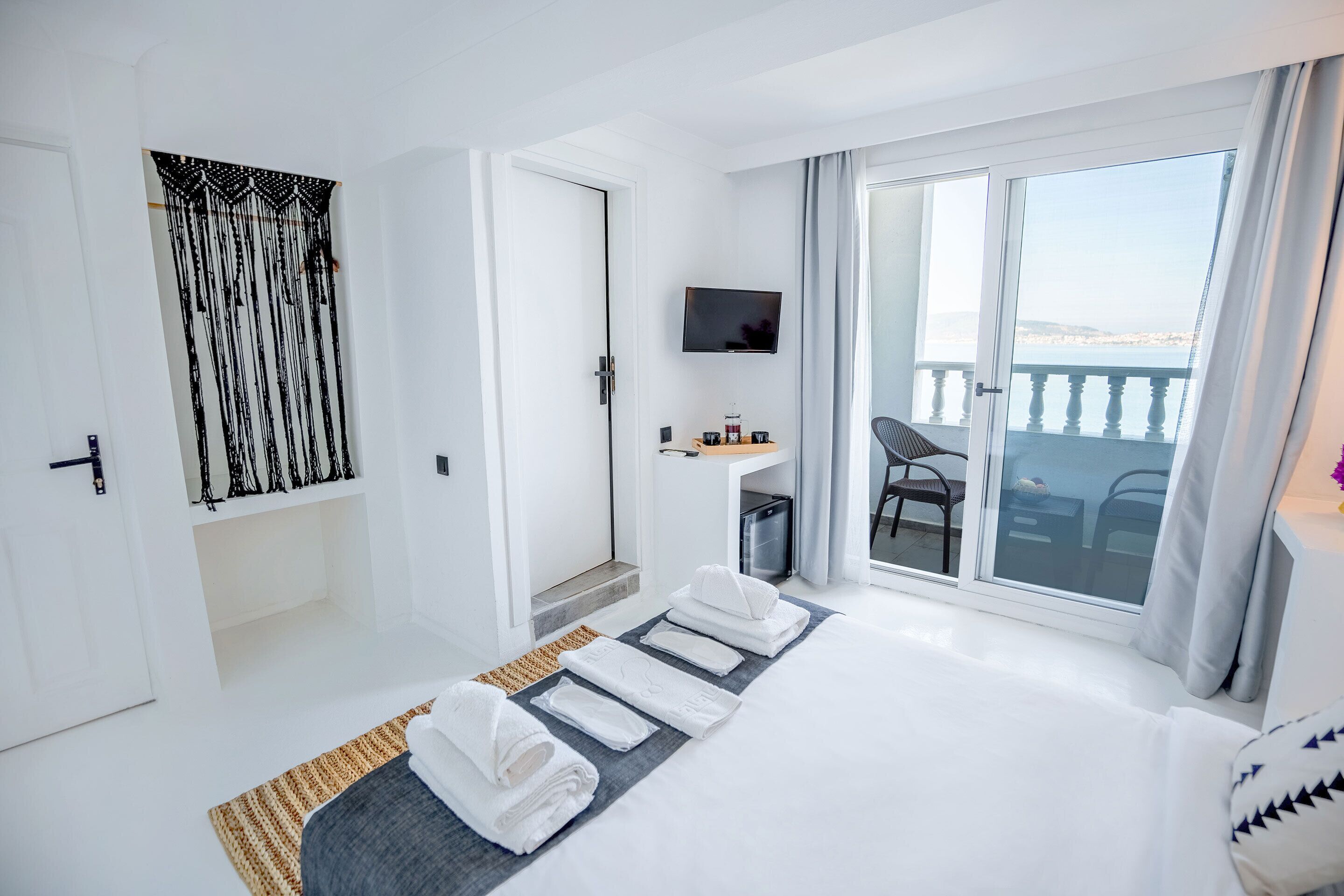 Habitación de hotel moderna con cama, televisión, una mesita con una silla y balcón con vistas.