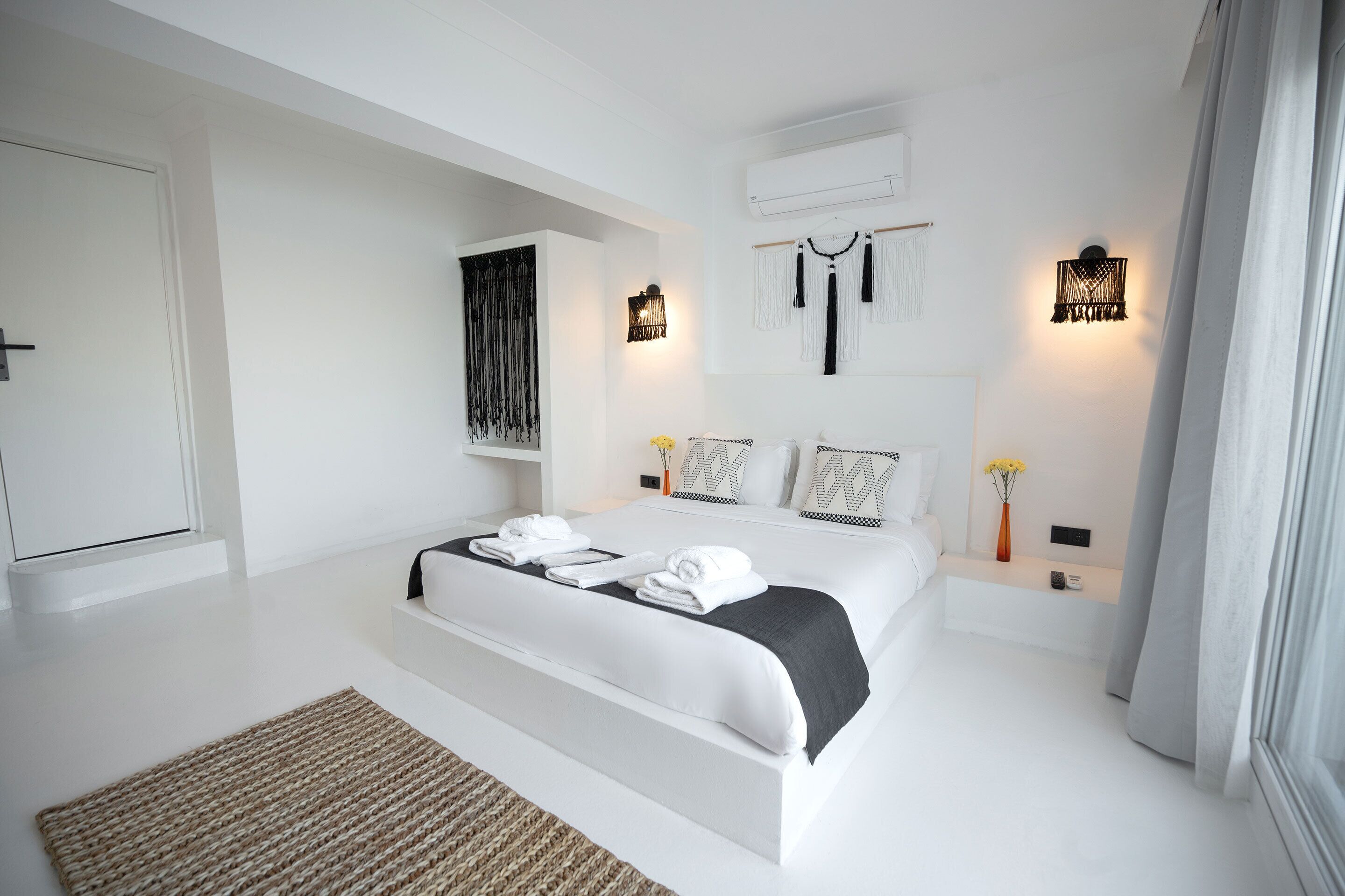 A modern bedroom with a large bed, white walls, and a minimalist design.