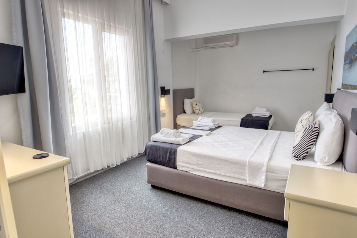 Une chambre d’hôtel avec un lit, un bureau, une télévision et une fenêtre avec des rideaux.