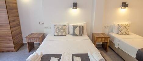 A hotel room with a large bed, two bedside tables, and a wooden wardrobe.