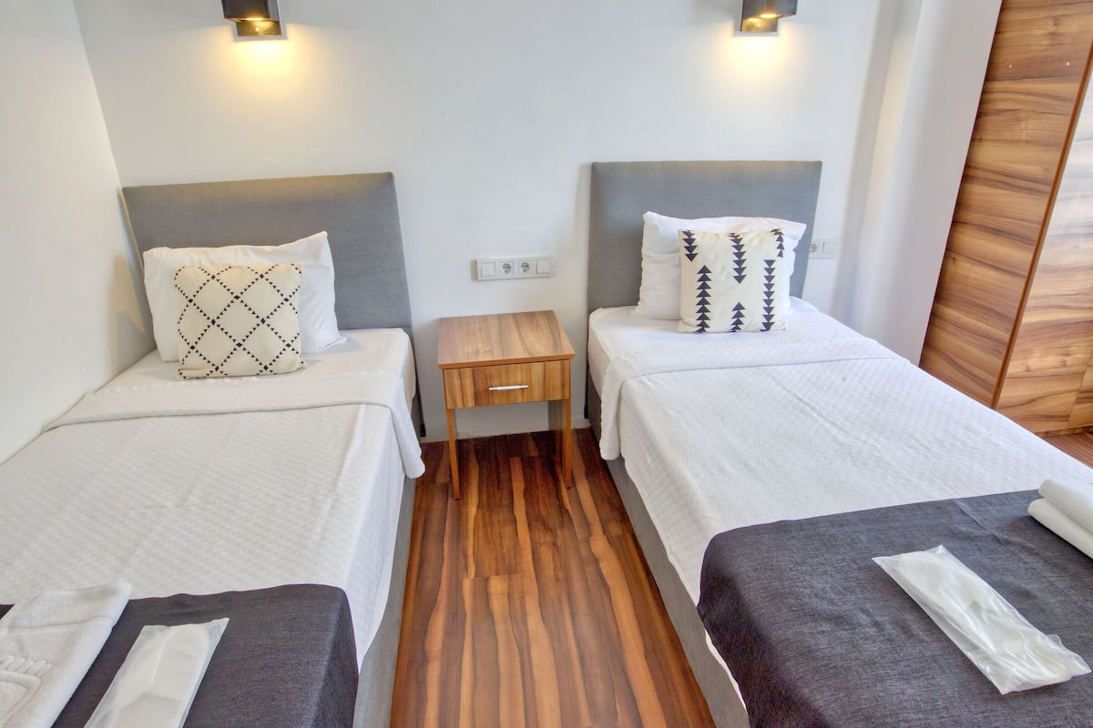 Une chambre d’hôtel avec deux lits, chacun étant équipé d’un oreiller et d’une table de chevet en bois.