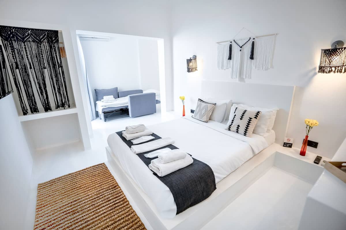 Une chambre d’hôtel moderne dotée d’un grand lit, d’un petit coin salon et offrant une vue sur l’extérieur.