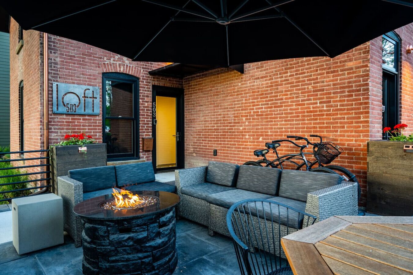 An outdoor seating area with a fire pit, sofas, and a table.