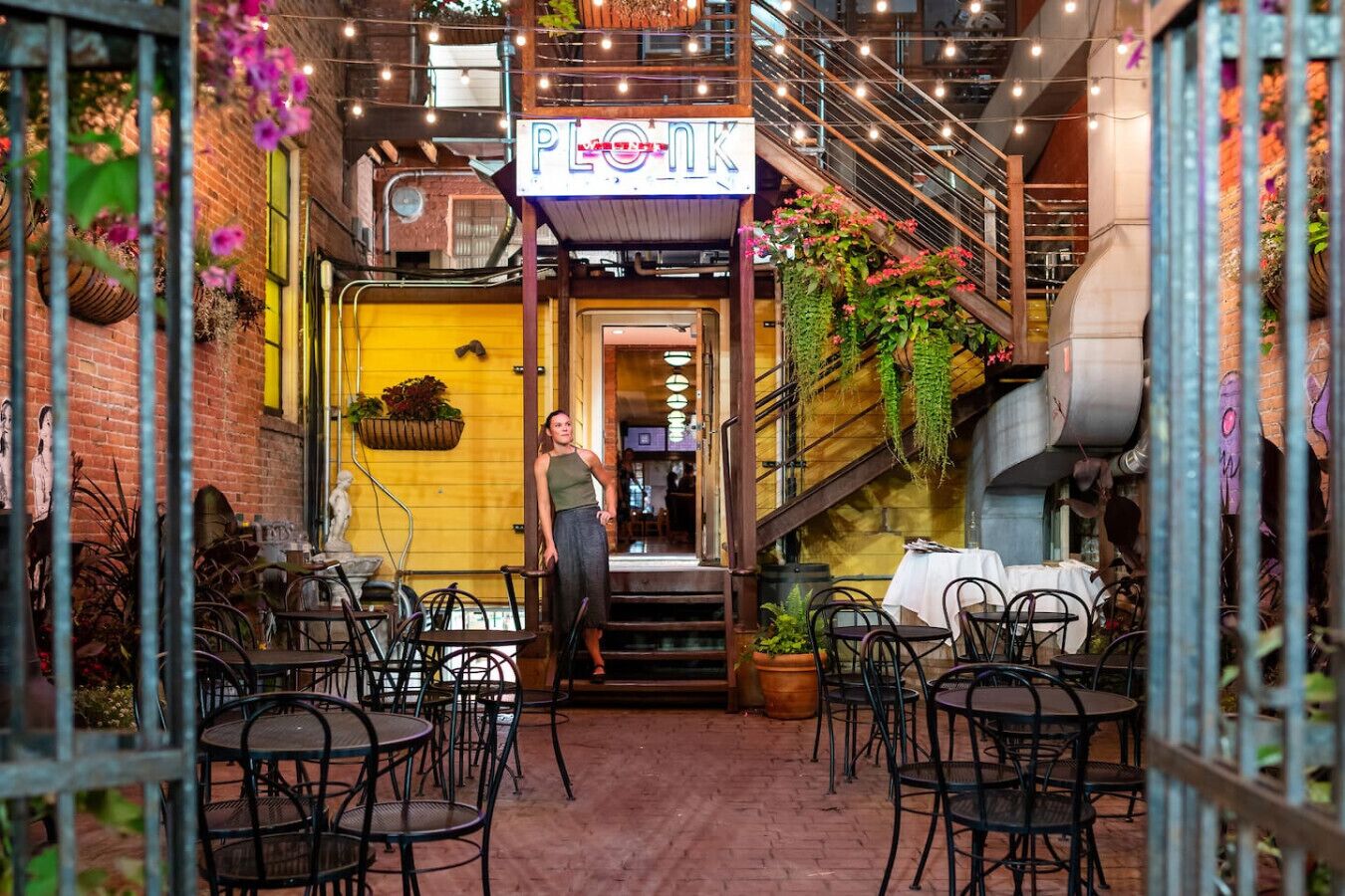 Een restaurant met terras, een trap en hangplanten.
