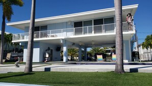 A two-story building with a balcony, palm trees, and a pool. - Coo Coo's Nest ~ Key Largo canal front 2/3 with pool (Key Largo)