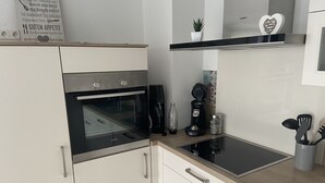 A kitchen with a built-in oven, a coffee maker, and a toaster. There are cabinets and a countertop. - Ferienwohnung mit Balkon (Bruttig-Fankel)