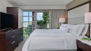 Camera d'albergo con un letto grande, una televisione, una scrivania con lampada e vista sull'esterno.