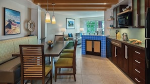 Una cucina moderna con mobili in legno, un backsplash in piastrelle blu e un'area pranzo con tavolo e sedie in legno.