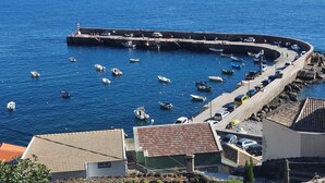 Un port de plaisance situé sur la côte, avec des bateaux amarrés et une jetée incurvée qui s’avance dans la mer.