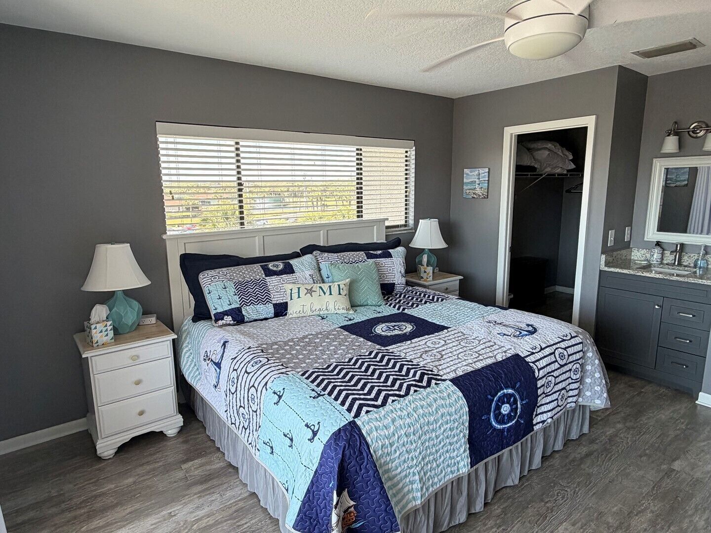 A bedroom with a bed, nightstands, a dresser, a closet, and a window with blinds.