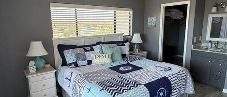 A bedroom with a bed, nightstands, a dresser, a closet, and a window with blinds.