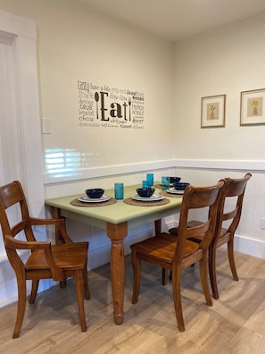 A dining area with a table set for four, wooden chairs, and a wall decal with food-related words. - Waterfront Historic Bungalow Three• Ferry to SF (Vallejo)