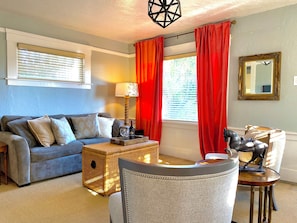 A living room with a sofa, a lamp, a wicker side table, and a decorative horse statue. - Waterfront Historic Bungalow Three• Ferry to SF (Vallejo)