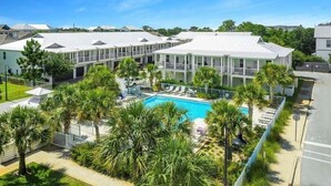 A hotel with multiple buildings, a swimming pool, and palm trees. - Seasonal Beach Service & Heated Pool + Golf Cart Included!! (Destin)