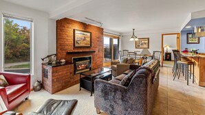 A living room with a fireplace, a dining area, and a kitchen.