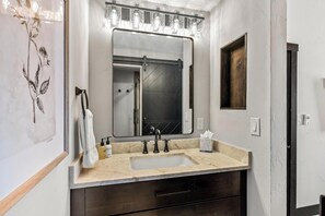 A bathroom with a large mirror, vanity, sink, and a towel rack. - Bear Claw 510 Exceptional Mountain Condo with Ski-In/Ski-Out Access! (Steamboat Springs)
