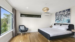 A bedroom with a large bed, a chair, a window, an air conditioning unit, and a ceiling light fixture. - Vue Sur La Mer (Wye River)
