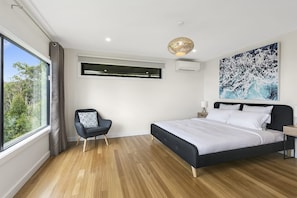 A bedroom with a large bed, a chair, a window, an air conditioning unit, and a ceiling light fixture. - Vue Sur La Mer (Wye River)