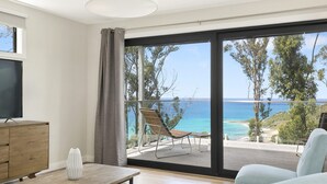 A room with a large sliding glass door leading to a balcony with a view of the sea. - Vue Sur La Mer (Wye River)