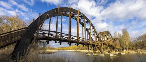 A large, historic water wheel structure spanning a river, surrounded by natural scenery and trees.