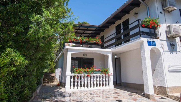 A white building with a balcony, a tiled entrance, and a small garden area. - Holiday apartment only 150 m from the sea (Artatore)