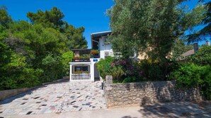 A building with a stone facade, a tiled entrance, and a balcony with potted plants. - Holiday apartment only 150 m from the sea (Artatore)