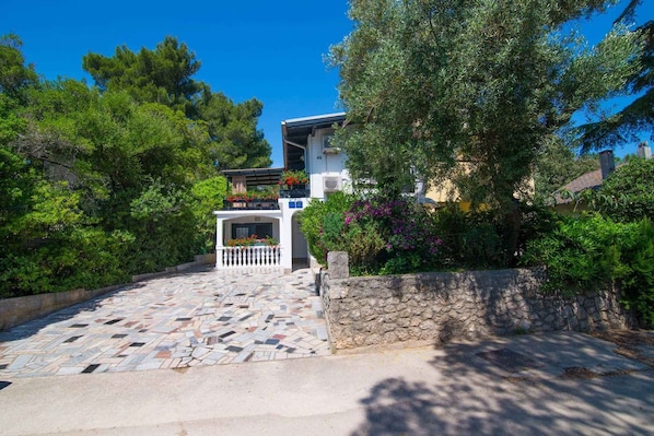 Un edificio de fachada de piedra, entrada con azulejos y un balcón con plantas en macetas.