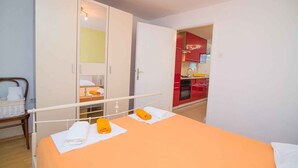 A bedroom with a bed, a wardrobe, and a view of a red kitchen. - Holiday apartment only 150 m from the sea (Artatore)