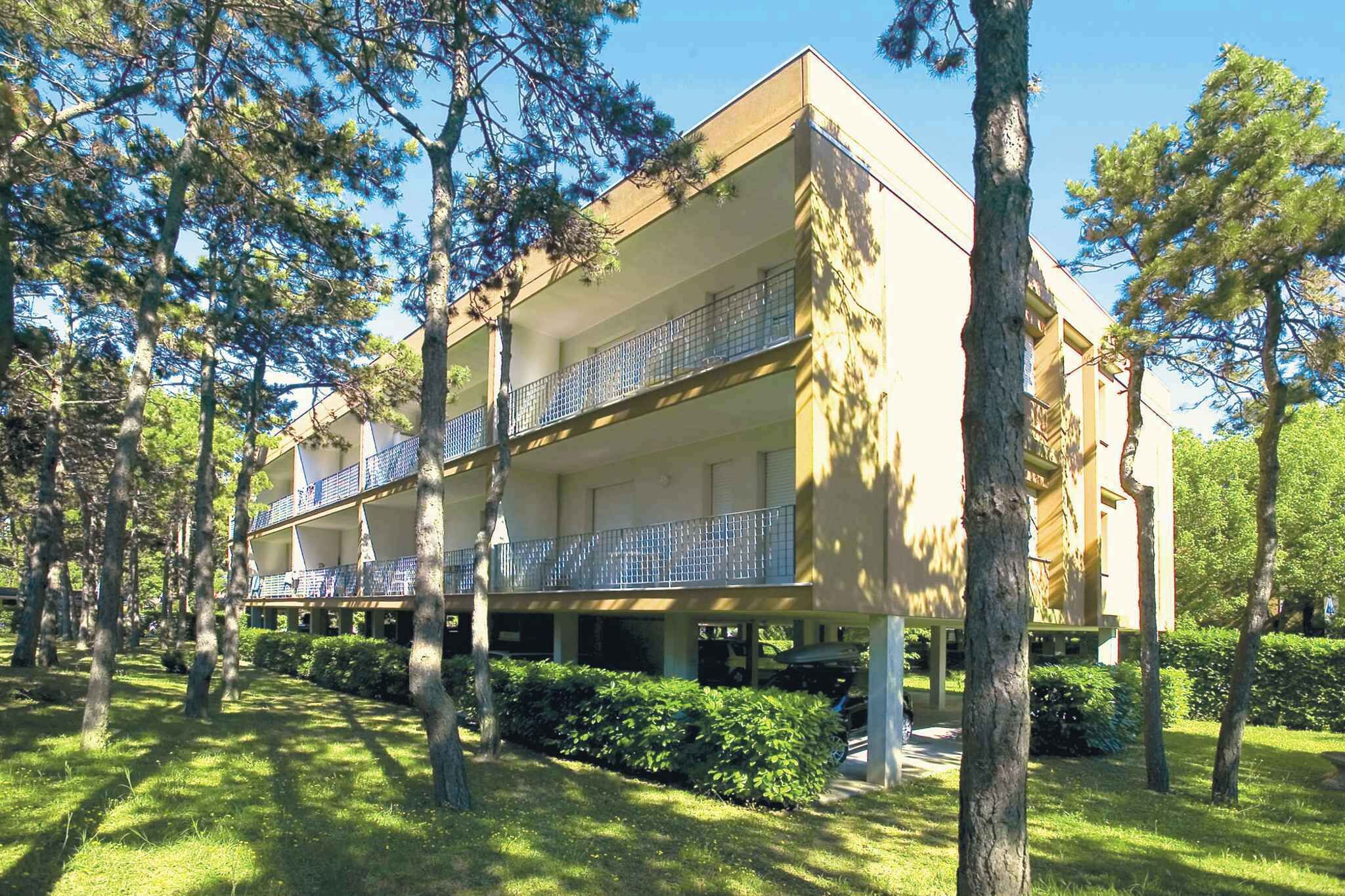 A multi-story hotel with balconies, surrounded by trees and greenery.