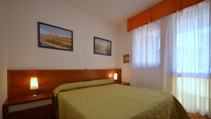 Ein Hotelzimmer mit einem Bett, zwei Nachttischlampen, einem Holzkopfteil und zwei gerahmten Bildern an der Wand.
