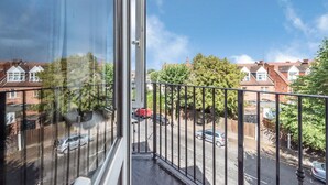 Un balcón con vistas despejadas a una calle residencial, casas y coches estacionados.
