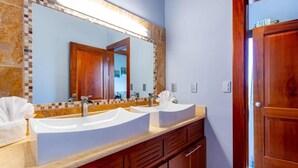 A bathroom with a double sink vanity, a large mirror, and wooden cabinetry. - Oceanview Condo w/ Picturesque Covered Terrace & Infinity Pool (Playa Flamingo, Cabo Velas)