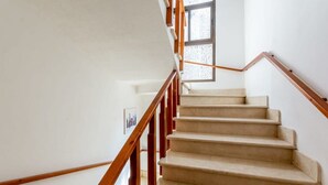 Una escalera con barandillas de madera y peldaños color beige.