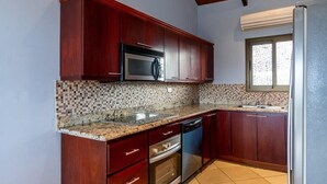 Una cocina con armarios de madera oscura, un microondas de acero inoxidable, un lavavajillas y un salpicadero de azulejos.