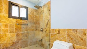 Un baño con ducha, inodoro y ventana.