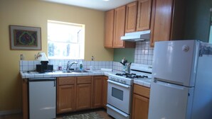 Una cocina con armarios de madera, una estufa blanca, un lavamanos y un refrigerador.