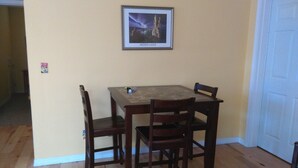 Un comedor con una mesa de madera y cuatro sillas, un cuadro enmarcado del Lago Mono en la pared, y una puerta blanca a la derecha.
